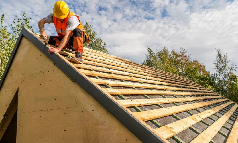 Roof framing construction in Los Angeles with worker installing wooden roof structure